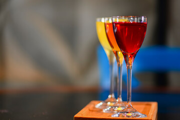 Three colorful refreshing cocktails served on a dark rustic wooden table with blurred background.