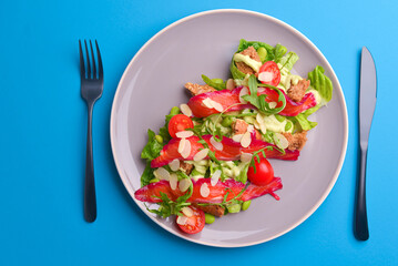 Fresh salad with smoked salted salmon, tomatoes and pumpkin seeds. Served on a gray plate over gray texture background.