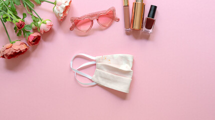 Summer concept. Flat lay with trendy mask, glasses, and feminine accessories on a pink background. Copy space