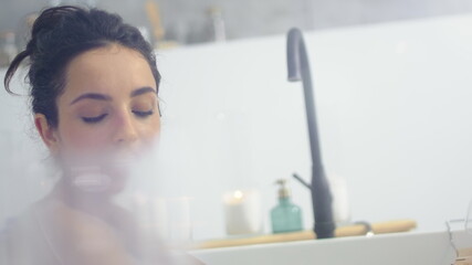 Close up sensual woman lying in bathtub with foam. Romantic girl resting in bath