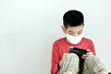 A boy playing a tablet on a white background