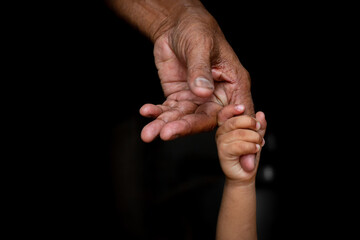 A baby's hands holding tightly A senior man's old age finger. Family, Generation, Support and...
