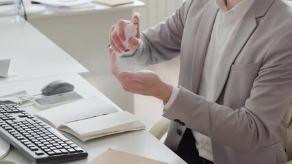 Mid-section shot of businessman in formalwear and face mask pushed to his chin applying hand sanitizer while working in office during pandemic - Powered by Adobe