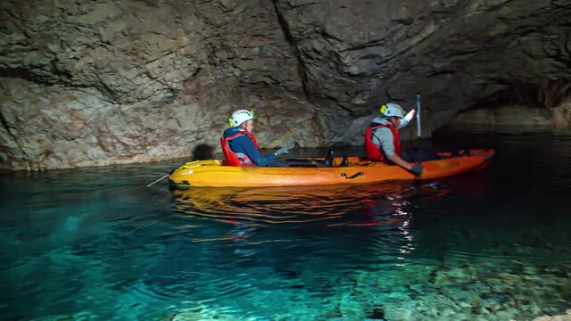 Group of tourists kayaking underground at cave in Peca, Slovenia. Slow motion