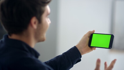 Cheerful making video talk on green screen mobile phone in slow motion