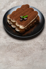 Classic tiramisu dessert on ceramic plate on light grey concrete background