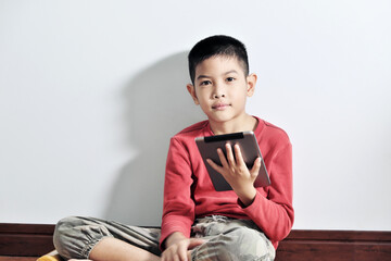 A boy playing a tablet on a white background