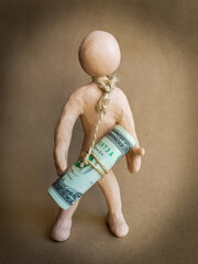 A figure of a man made of plasticine with a rope around his neck, to which banknotes are tied. Concept: debt, tax, depression, financial problems, mortgage, credit, crisis. Noise / grain, vignetting.