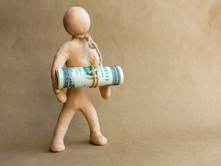 A figure of a man made of plasticine with a rope around his neck, to which banknotes are tied. Concept: debt, tax, depression, financial problems, mortgage, credit, crisis. Noise / grain, vignetting.