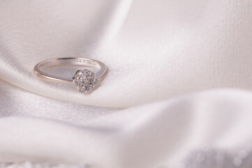 A wedding ring with diamonds topping,isolated over silky satin background