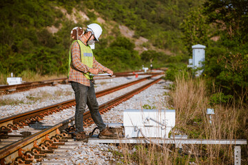 The engineer under inspection and checking construction railroad station .Engineer wearing safety uniform and safety helmet in work wearing mask for safety from virus. 