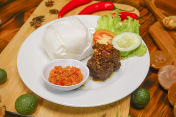 beef rendang with rice on white plate wooden board background. Indonesian famous food