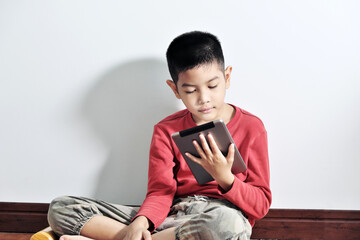 A boy playing a tablet on a white background