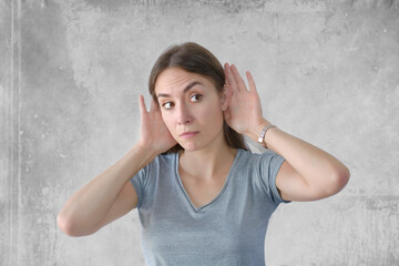 Young beautiful woman over background with hand over ears listening
