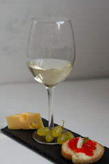 sandwiches with red caviar and belm wine on a black stone board