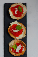 sandwiches with red caviar on a black stone board