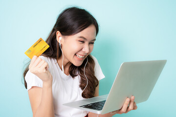Young asian woman using laptop with happy and showing a gold credit card while shopping online.