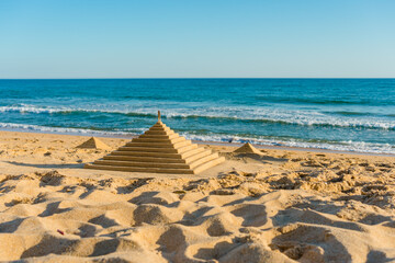 Fototapeta na wymiar Beautiful sandcastle pyramids made on sand beach natural outdoors background.