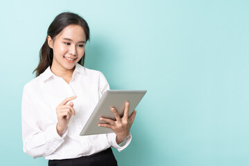 Fototapeta premium Portrait of young asian woman working online on tablet with happy on blue background with free copy space. Wireless connection technology concept.