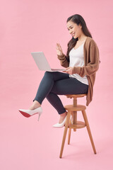 Cheerful woman sitting on chair and using laptop