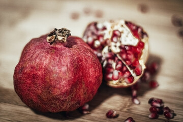 pomegranate with sprinkled grains on a wooden background