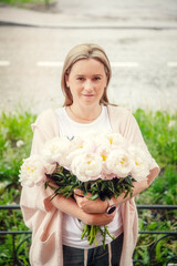 Portrait of a woman with peonies on the street