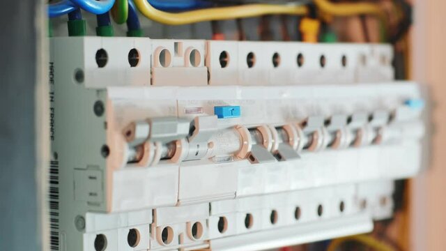 Close-up Of Hand On Switch Of Distribution Board. Man switching on fuseboard