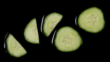 Fresh cucumber slices isolated on black background, top view