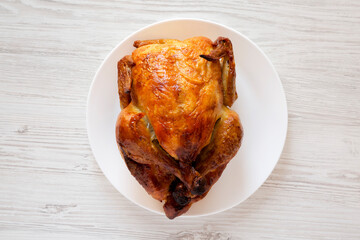 Homemade traditional rotisserie chicken on a white plate, top view. Flat lay, overhead, from above.