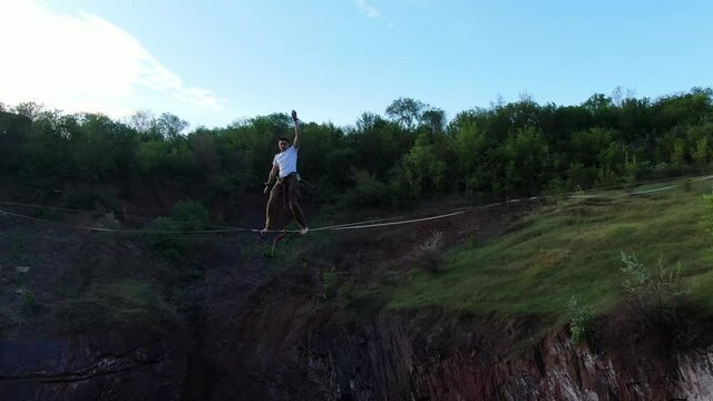 Extreme sport, a man is falling from a slackline over the pit, safe cable, 4k