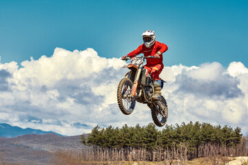 Fototapeta na wymiar Motocross concept, a biker goes off-road making extreme skiing. In pursuit of adrinalin, sport concept. Dangerous sport.