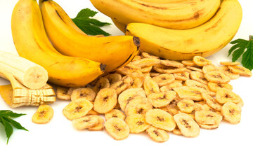 Heap of dried banana chips with yellow banana bunch and green leaves