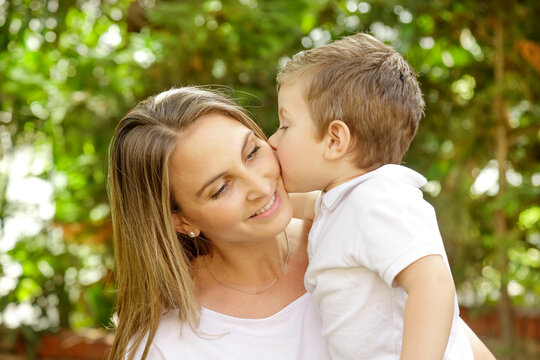 bambino abbraccia teneramente la madre e la riempie di baci nel giardino di casa