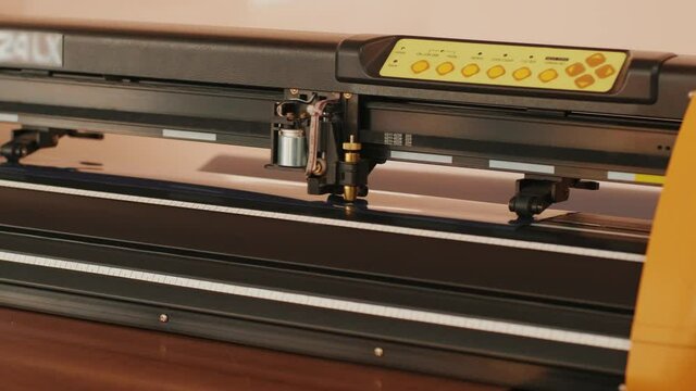 Cnc machine cuts logo on tracing paper from plastic film. Cutting machine stickers. Cutting plotter.