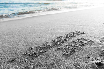 2020 Vacation handwritten on sandy beach natural outdoors background.
