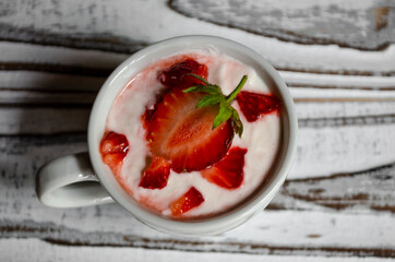 strawberry yogurt in a white cup with mint and fresh strawberries