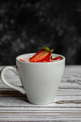 strawberry yogurt in a white cup with mint and fresh strawberries