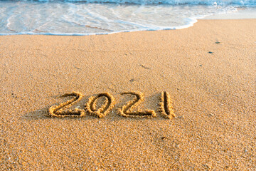2021 year handwritten on sandy beach natural outdoors background.