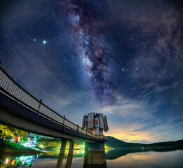 Night landscape at a hydroelectric dam with galaxies shining in the sky. This is power supply to...