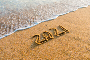 2021 year drawing on the sand at the beach.