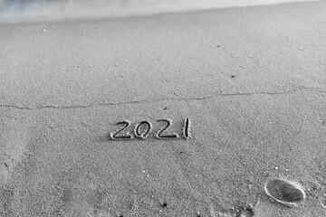 2021 year drawing on the sand at the beach.