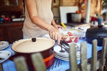 Woman preparing food and feast for summertime lunch at countryside rustic cottage outdoor kitchen.
