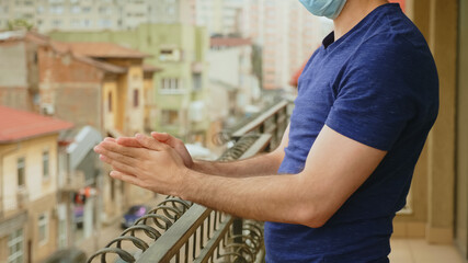 Man on balcony clapping in support for doctors during global pandemic lockdown