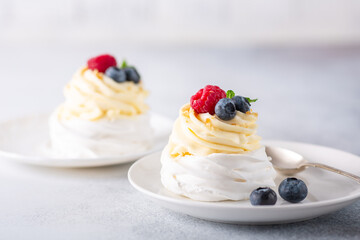 Delicious Pavlova cake with whipped cream and fresh berries on white plate. Stone background. Selective focus