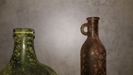 large vintage vases or jugs of colored glass as decoration elements in a modern interior near a gray concrete wall. Decoration of an apartment or house.