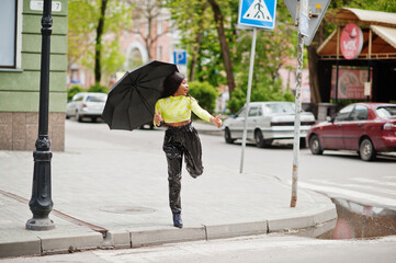 Portrait of young beautiful african american woman holding black umbrella try to catch taxi.