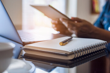 Woman hand holding and using digital tablet, work on laptop computer with notebook and pen on the...