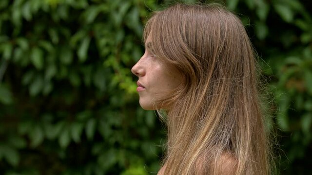 Profile of an attractive young woman with a serious expression on her face against a green floral background