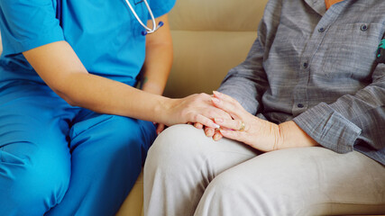 Close up of female caretaker in nursing home holding senior woman hand. Social worker