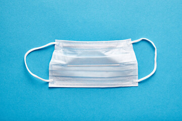Close-up of medical mask on blue background, top view. Concept of mutual medical assistance and...